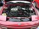1991 Ford Probe - Very small, low-resolution thumbnail of an open engine bay on a red car, with the hood raised and a transverse engine visible under a black…