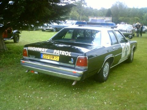 1991 Ford Crown Victoria - Rear view of a 1991 Ford Crown Victoria marked as Highway Patrol, parked outdoors with other vehicles.