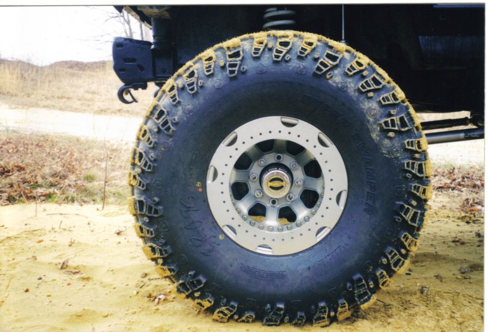 Super Swamper mud tire on polished 8-lug wheel, caked in yellow clay