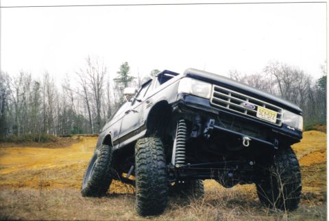 1988 Ford Bronco - Ford Bronco with custom suspension and tires navigating an off-road course.