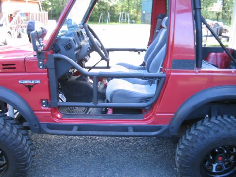 1987 Suzuki Samurai - The interior of a red Suzuki Samurai is visible, roll cage and custom seats.