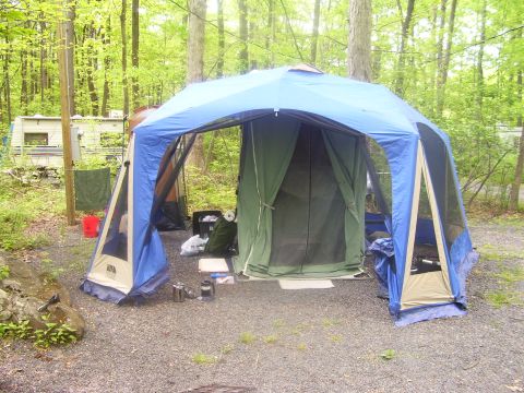1991 Ford Bronco - A campsite scene features a large multi-room tent set up, with an RV visible in the wooded background.