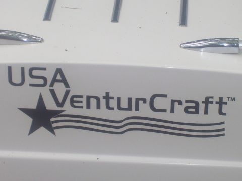 1991 Ford Bronco - Extreme close-up of a white fiberglass hull or trailer panel wearing a black "USA VenturCraft" decal with a star-and-stripes logo, above a…