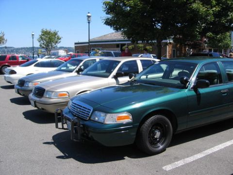 1999 Ford Crown Victoria - Several Ford Crown Victorias are parked in a row on a sunny day.