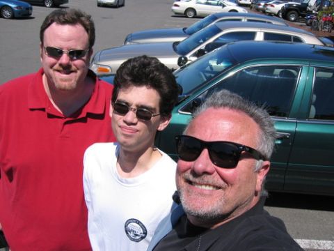 1999 Ford Crown Victoria - Three men are photographed in front of several parked vehicles.