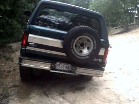 1996 Ford Bronco - Rear view of a dark green 1996 Ford Bronco with a spare tire and chrome bumper.