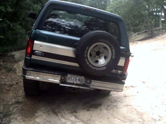 Dark green 1996 Ford Bronco with a silver stripe, spare tire mounted on the rear, and a chrome bumper