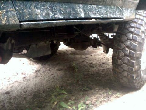 1996 Ford Bronco - The underside of a muddy 4x4 shows its suspension and large off-road tire.