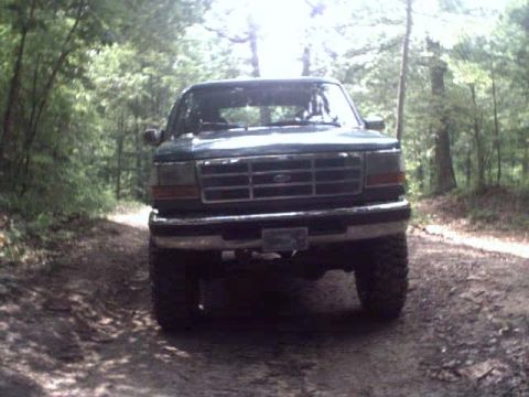 1996 Ford Bronco - A green 1996 Ford Bronco is seen from the front on a wooded dirt road.