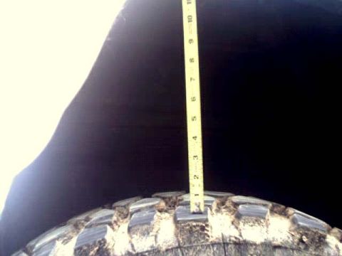 1996 Ford Bronco - A yellow ruler is used to measure the depth of the tread on a large tire.
