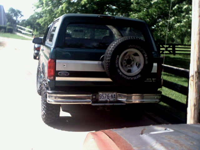 Rear view of a lifted 1996 Ford Bronco in green with a spare tire mounted externally