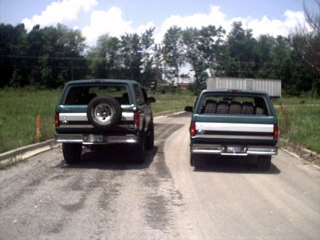 Two green 1996 Ford Broncos from the rear, one with a spare tire mounted externally