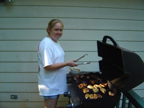 1986 Ford Bronco - Woman grilling chicken outdoors in front of a wood-paneled wall.