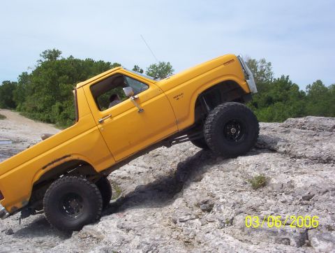 1991 Ford Bronco - Yellow Ford Bronco navigating rocky terrain off-road.