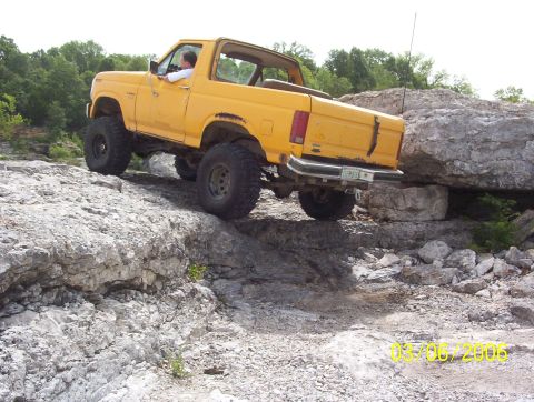 1991 Ford Bronco - This yellow SUV is navigating a rocky off-road course, with a driver behind the wheel.