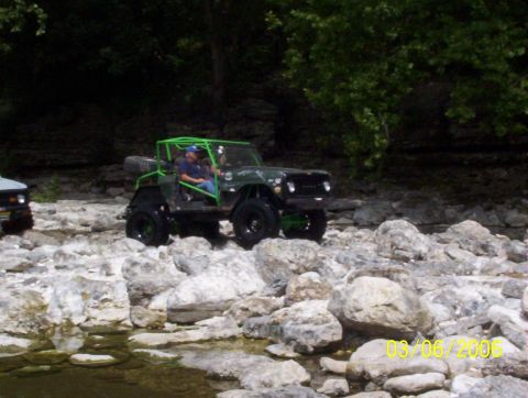 1991 Ford Bronco - A modified 1991 Ford Bronco navigates a rocky terrain near a stream.