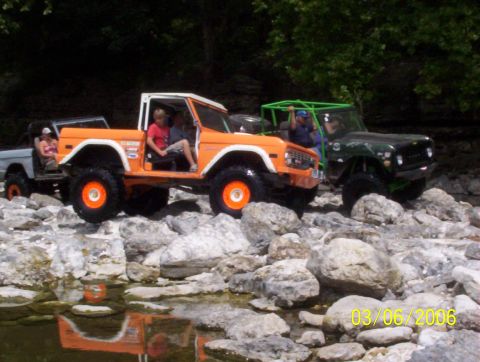 1991 Ford Bronco - An orange 1978 Ford Bronco navigates a rocky terrain, with another off-road vehicle visible behind it.