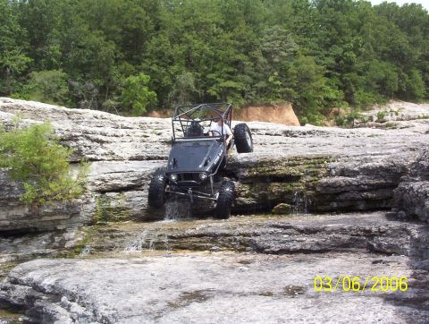 1991 Ford Bronco - An off-road vehicle tackles a challenging rocky stream crossing on a sunny day.