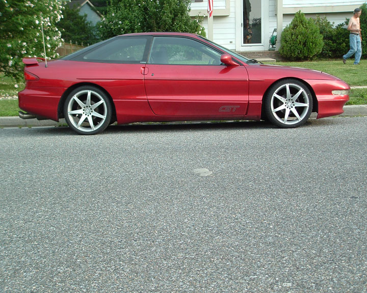 Red Ford Probe GT coupe profile lowered on chrome wheels at street curb