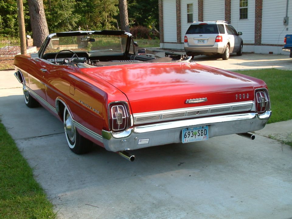 Red 1967 Ford Galaxie 500 convertible, top down, rear three-quarter view on a driveway