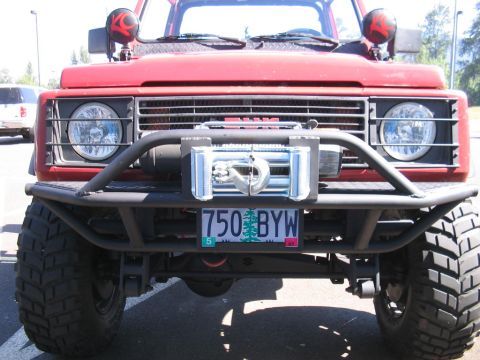 1987 Suzuki Samurai - A red 1987 Suzuki Samurai is equipped with a winch and custom bumper, seen from the front.