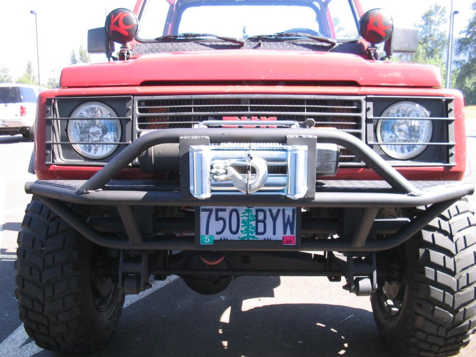 Red 1987 Suzuki Samurai with a winch and off-road bumper, front view