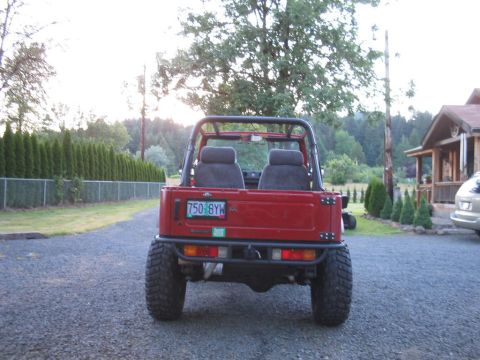 1987 Suzuki Samurai - Rear view of a red 1987 Suzuki Samurai parked on a gravel driveway.