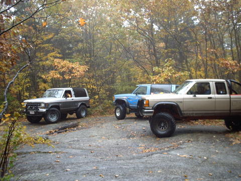 1990 Ford Ranger - A gray Ford Bronco II and a tan Ford Ranger are parked off-road in a wooded area during autumn.