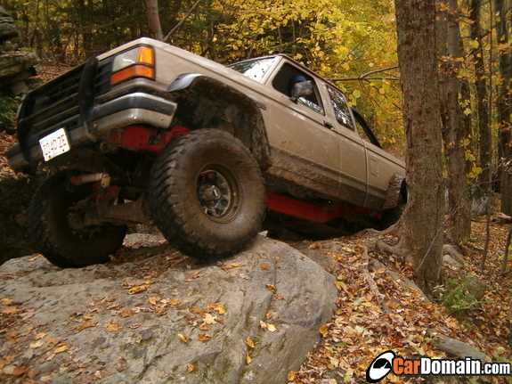 1990 Ford Ranger climbing over rocks on a wooded trail
