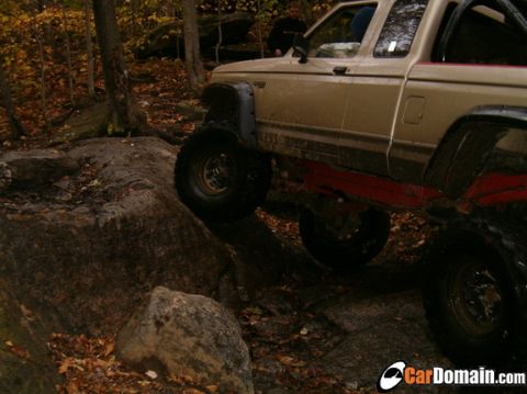 1990 Ford Ranger - A pickup truck navigates a rocky off-road course in a wooded area.