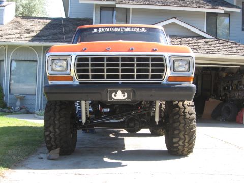 1979 Ford Bronco - This lifted Ford Bronco features a prominent grille and large off-road tires, with a website address visible on the windshield.