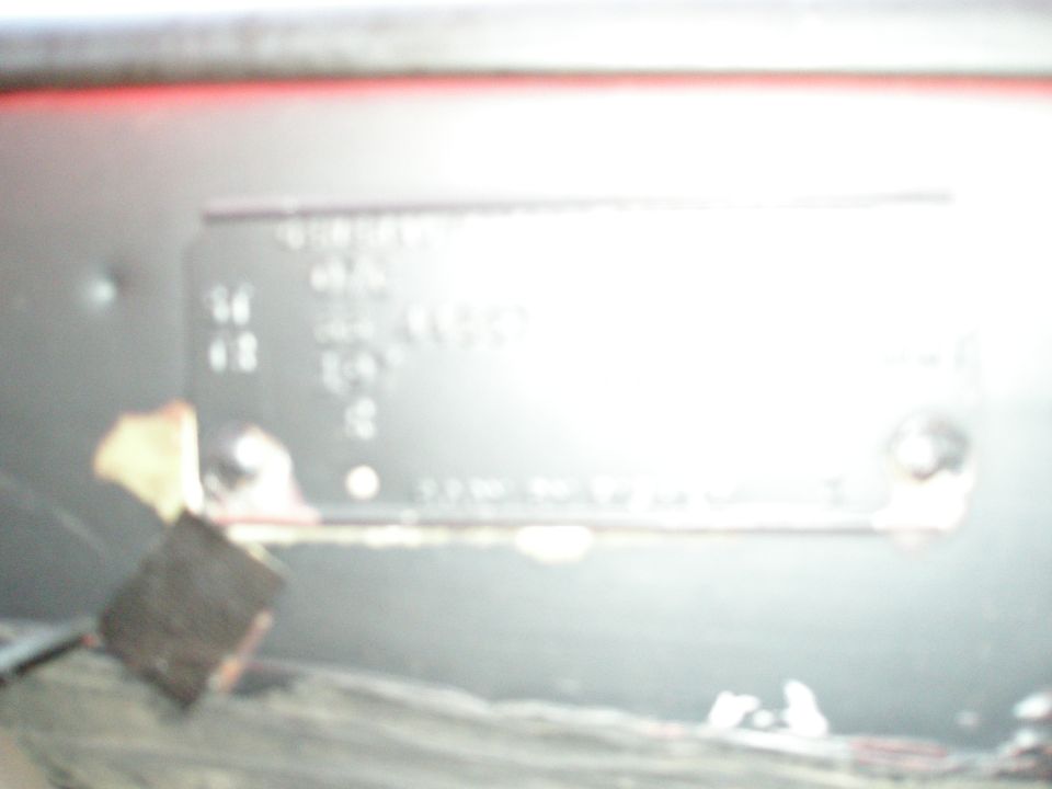 Blurry close-up of a metal vehicle data plate with glare