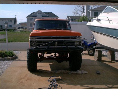 1978 Ford Bronco - This orange pickup truck is parked in a garage, next to a boat and a blue ATV.