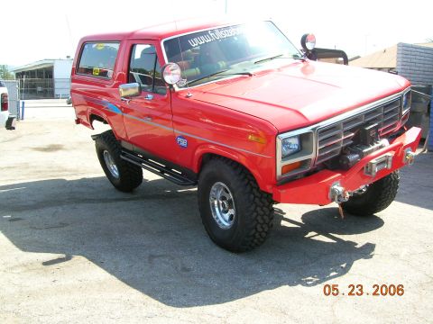 1985 Ford Bronco - This red Ford Bronco features a custom front bumper with a winch, and a "www.fullsizebronco.com" sticker on the windshield.