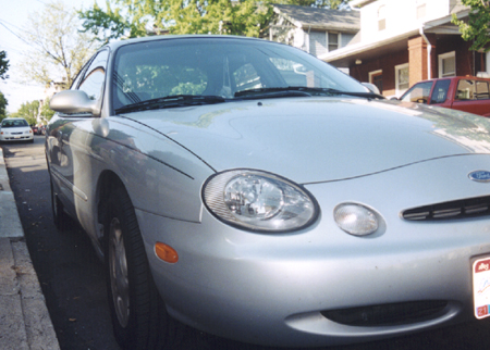 1997 Ford Taurus - A silver 1997 Ford Taurus is parked on a street, with another car visible in the background.