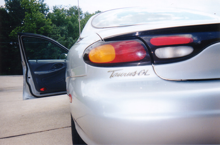 1997 Ford Taurus - The rear of a silver sedan is shown with the driver's side door ajar, revealing the interior.