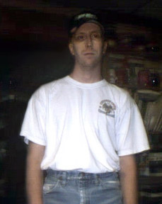 1996 Ford Bronco - Man in a white t-shirt and jeans stands indoors, with a logo visible on his shirt.