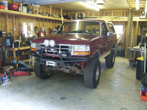 1993 Ford Bronco - This lifted Ford Bronco is parked inside a cluttered garage, ready for off-road adventures.