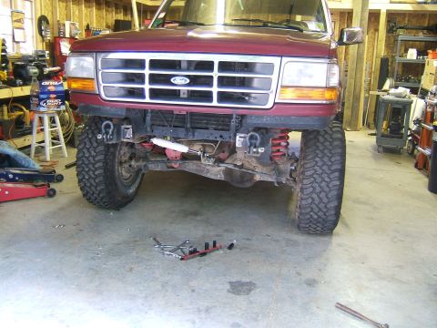 1993 Ford Bronco - The front grille and headlights of a maroon Ford truck are visible, with suspension components exposed.