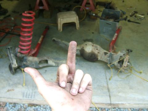 1993 Ford Bronco - Vehicle axle and suspension parts are laid out on the floor, with a hand gesture in the foreground.