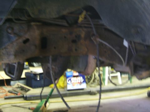 1993 Ford Bronco - The underside of a vehicle is shown, with various mechanical components and a Bud Light box in the background.