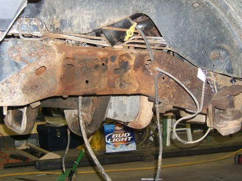 1993 Ford Bronco - Close-up of heavily rusted vehicle frame and suspension parts with a box of Bud Light visible.