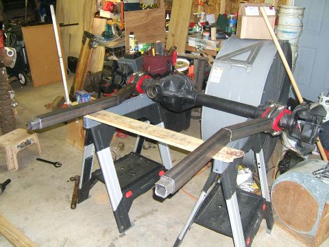1993 Ford Bronco - Custom axle assembly with fabricated extensions, set up in a workshop for modification.