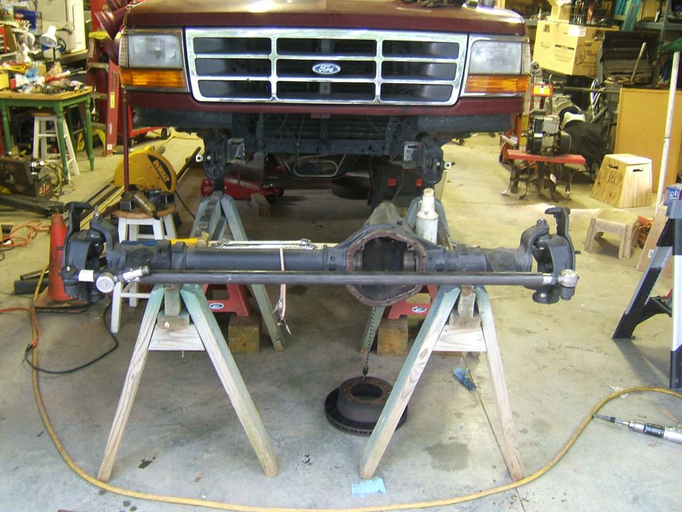 Maroon 1992 Ford Bronco front end with axle removed and supported on sawhorses