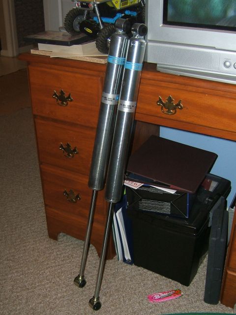 1993 Ford Bronco - A pair of Bilstein shock absorbers are shown indoors, resting near a dresser and entertainment center.