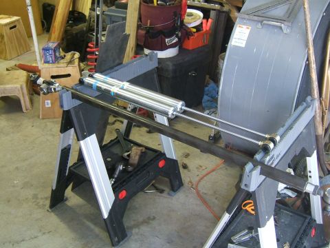1993 Ford Bronco - Dual shock absorbers are mounted on a metal rod supported by sawhorses in a workshop.
