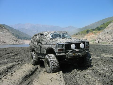 1985 Ford Bronco - This 1985 Ford Bronco is heavily covered in mud after navigating a challenging off-road terrain.