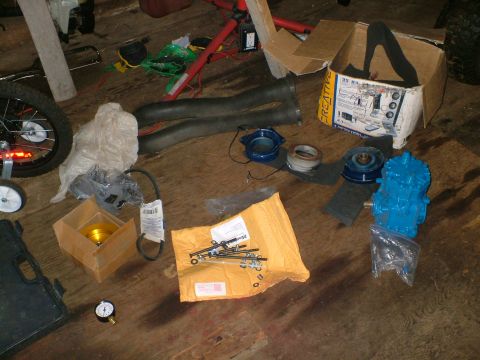 1989 Ford Bronco - Various automotive parts and tools are laid out on a wooden floor, possibly for installation or repair.