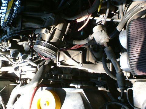 1989 Ford Bronco - Close-up view of an engine bay, showing the air filter, compressor, and various hoses and belts.