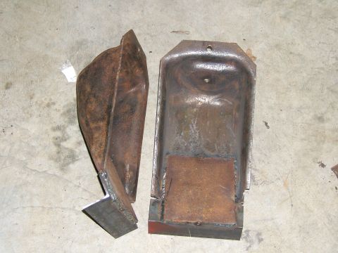 1993 Ford Bronco - Two rusty, possibly custom-made metal brackets sit on a concrete surface.